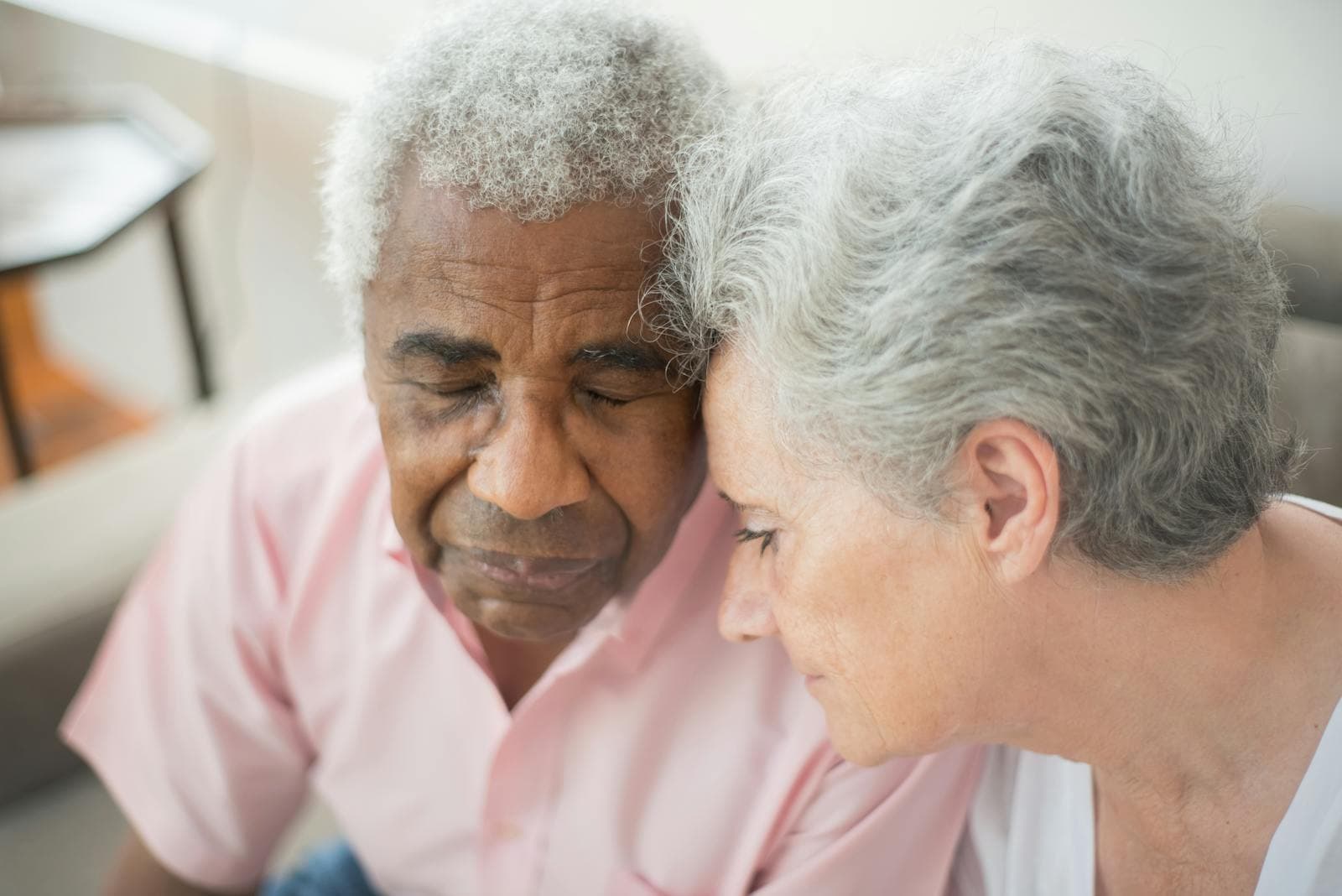 An elderly couple shares a tender moment at home — a common scene when one spouse is the dementia caregiver.
